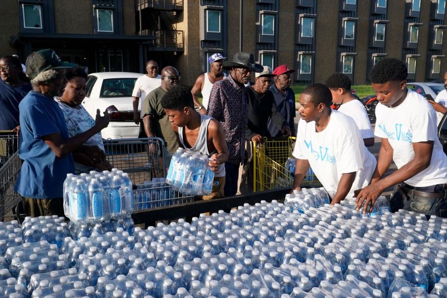 This photo features Black Jackson residents picking up containers of water in plastic bottles.