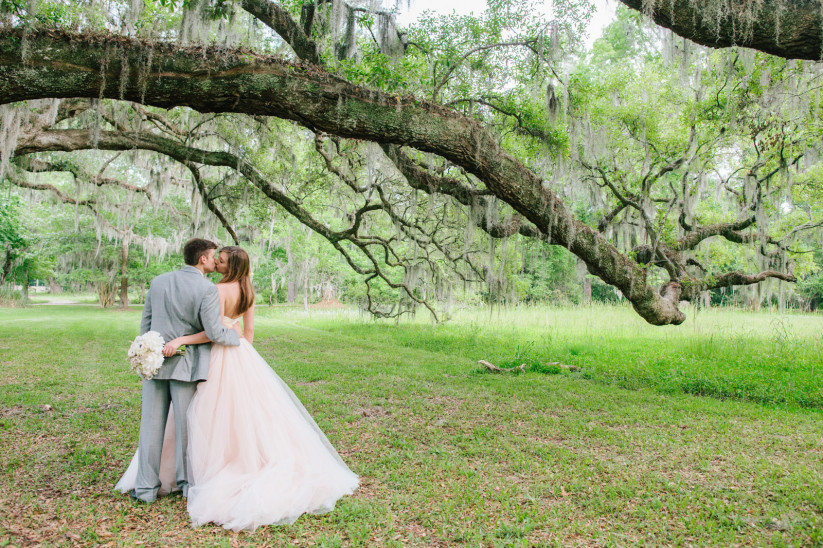 White bride and groom kissing on a plantation